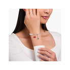 Bracelet charm featuring Eiffel Tower and red lips charm, worn elegantly by a woman.