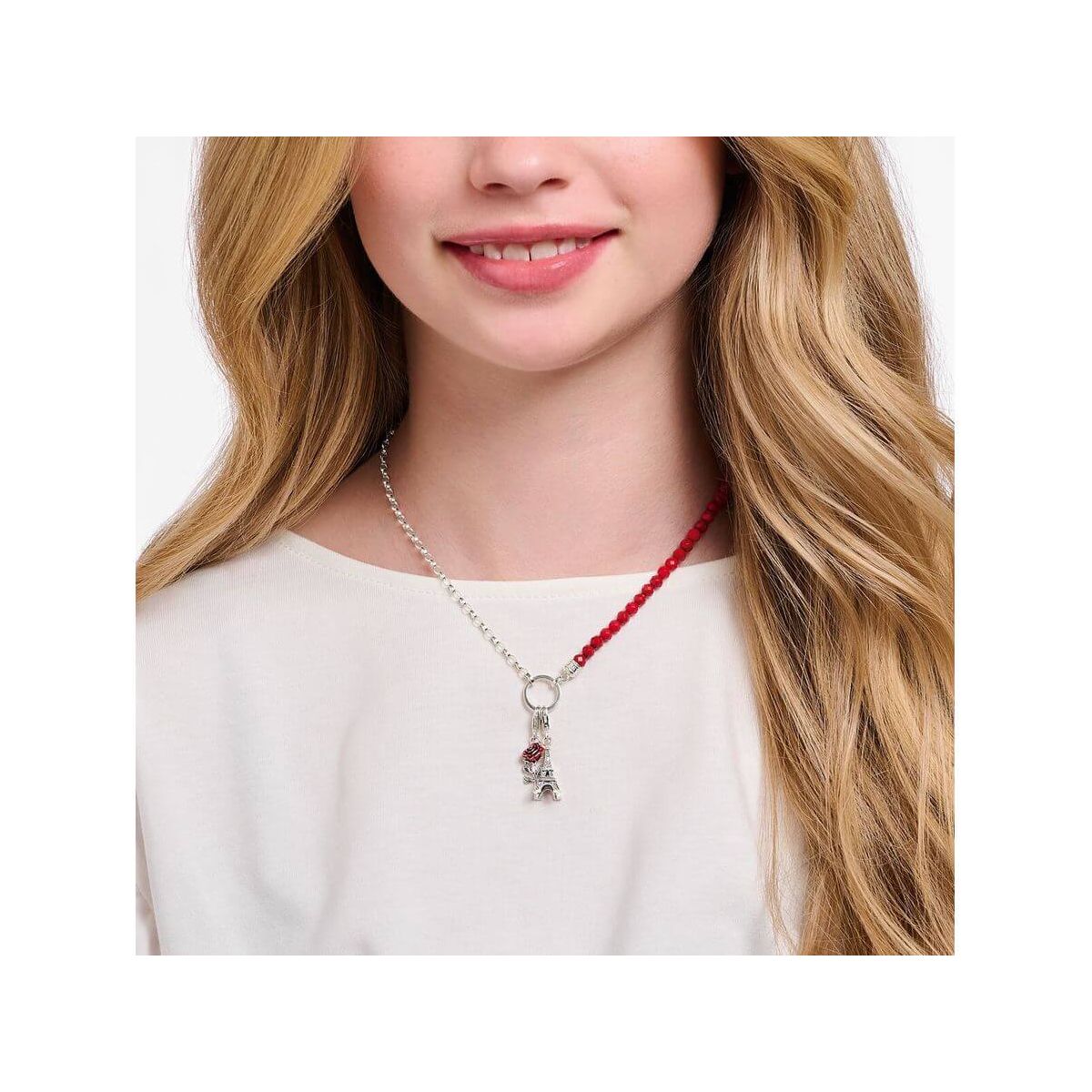 Femme avec un pendentif charm en argent et une rose rouge sur un collier élégant.