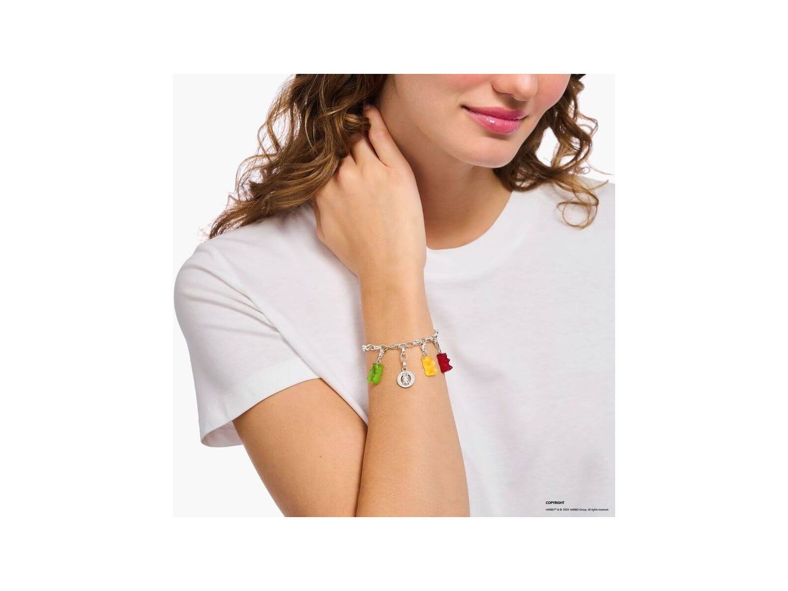 Bracelet charm with colorful gummy bear charms worn by a woman on her wrist, showcasing playful elegance.