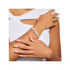 Femme portant un bracelet perle avec pendentif charm cœur en argent et saphir rouge, style élégant et raffiné.