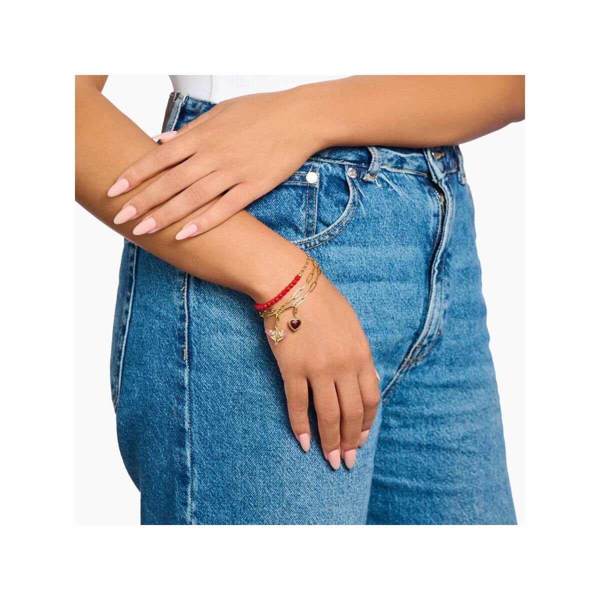 Femme portant un bracelet ajusté avec des perles rouges et un coeur, sur un fond en jeans.