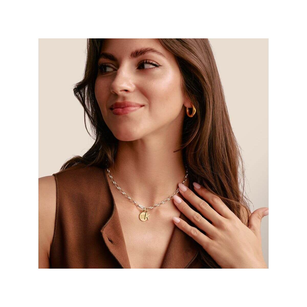 Femme portant un collier en argent avec un pendentif doré et des boucles d'oreilles en or, affichant un style élégant.