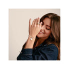 Femme souriante portant un bracelet avec un pendentif cœur en argent, mettant en valeur un style élégant et personnel.