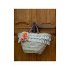 Stylish wicker basket adorned with white fringe and vibrant orange flowers, perfect for bohemian chic decor.