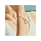 Pendentif charm papillon en plaqué or, porté sur bracelet délicat, capturant l'élégance estivale.