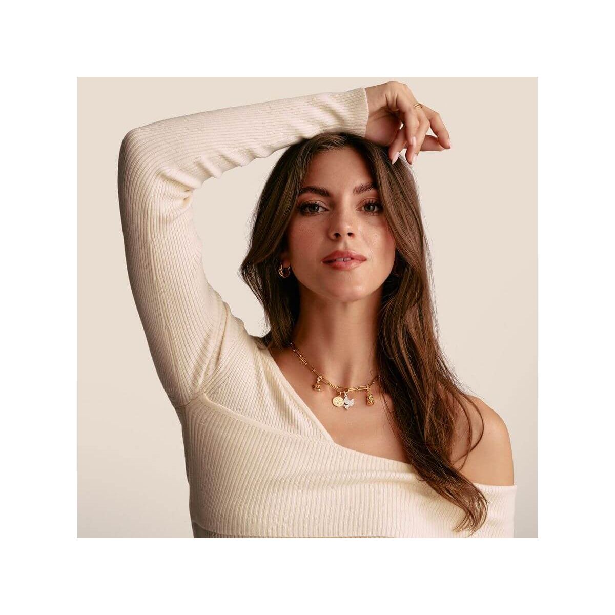 Modèle présentant un pendentif charm en or avec pierres blanches, dégageant élégance et style unique.