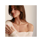 Femme portant un pendentif charm libellule en or plaqué avec des pierres blanches, mettant en valeur un style élégant.