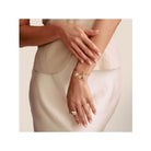 Femme portant un bracelet charm avec symbole infini et pendentifs en argent et or, mettant en valeur l'élégance et le style.