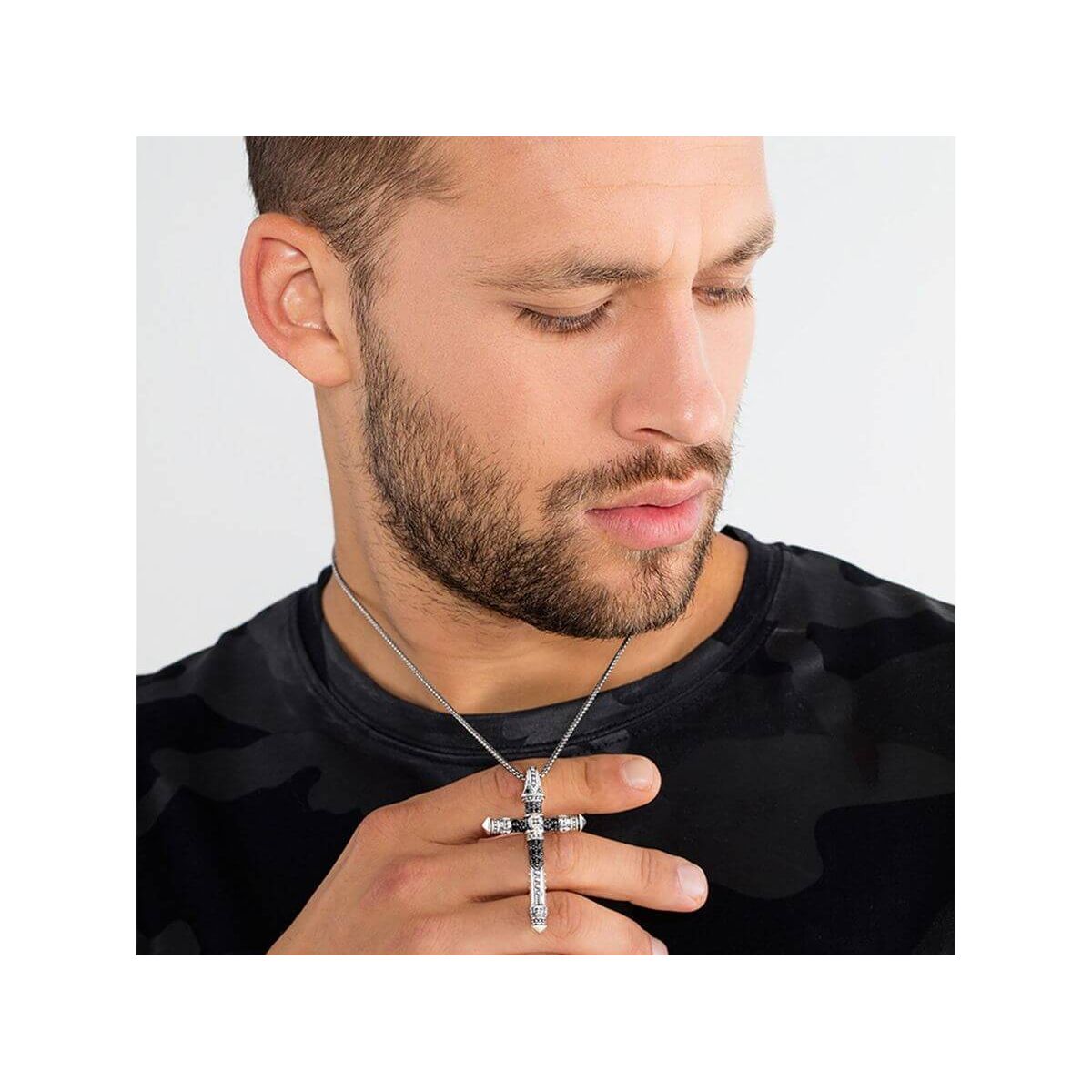 Homme portant un pendentif croix en argent avec une chaîne, affichant un look tendance et moderne.