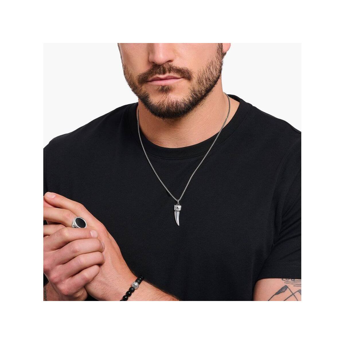 Homme portant une chaîne à breloque dent ornée de gemmes en argent noirci, style élégant.