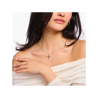 Femme portant une chaîne avec un pendentif croix blanche en argent recyclé et un bijou vintage.