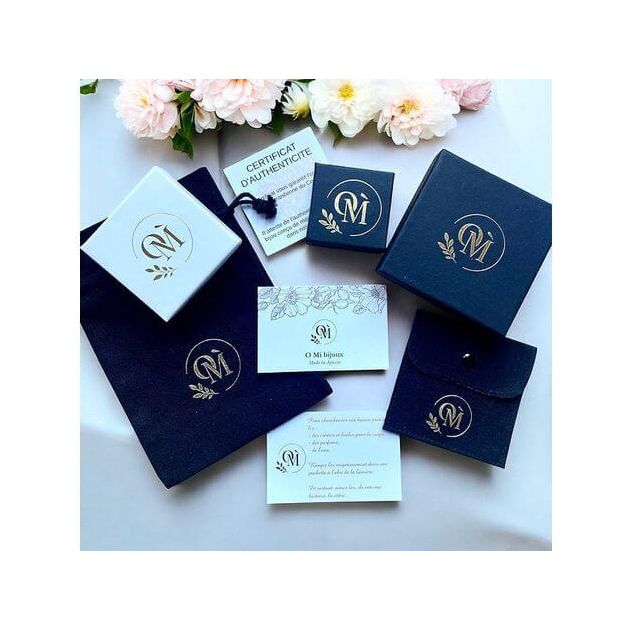 Image showcasing elegant jewelry packaging, including boxes and authenticity certificate, with floral accents.