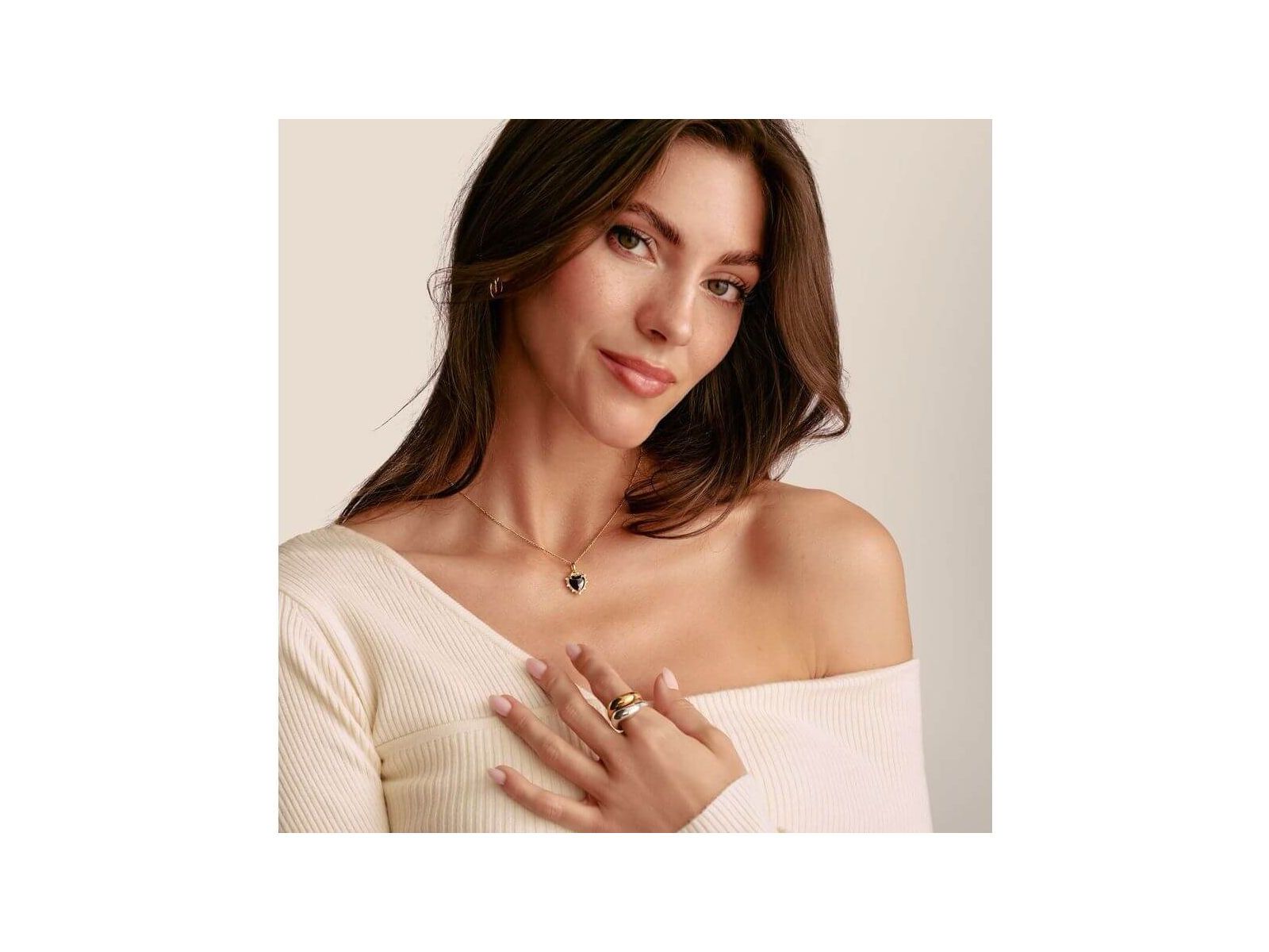 Femme portant un pendentif cœur vintage noir en argent plaqué or et des bagues, stylée et élégante.
