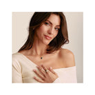 Femme portant un pendentif cœur vintage noir en argent plaqué or et des bagues, stylée et élégante.