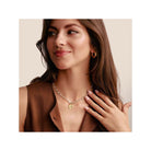 Femme souriante portant un collier chaîne avec un pendentif en or, affichant un style élégant et moderne.