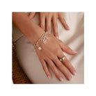 Bracelet charm argent avec étoile, croix et cœur, porté sur une main élégante, mettant en valeur un style unique.