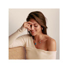 Woman wearing the Charm Ours d'Or pendant, smiling while showcasing its elegance on a stylish top.