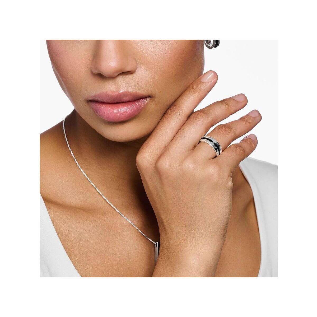 Femme portant une bague ruban en argent avec pierres noires, mettant en valeur son élégance et son style.