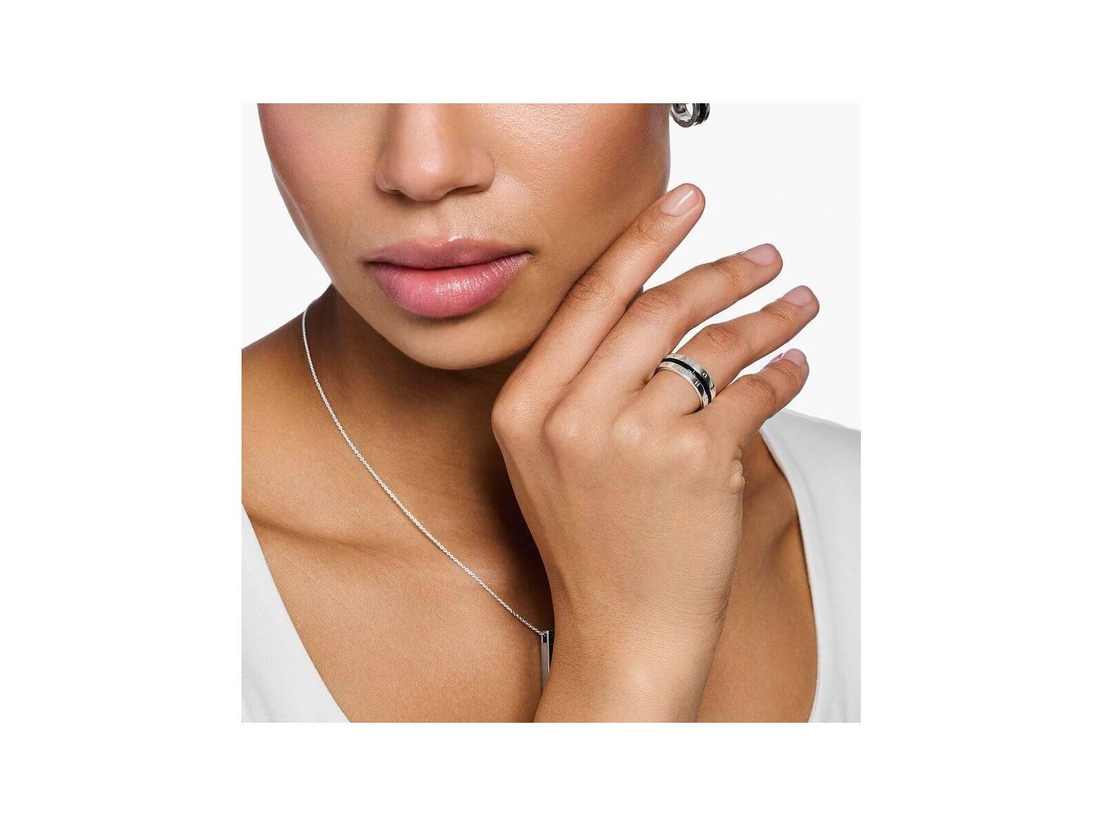 Femme portant une bague ruban en argent avec pierres noires, mettant en valeur son élégance et son style.