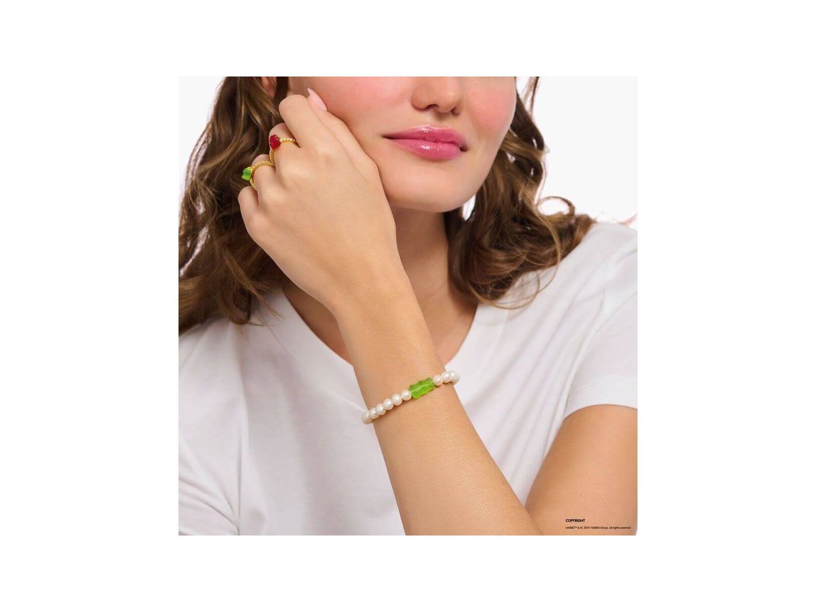 Bracelet de perles d'eau douce avec ours d'or vert sur le poignet d'une femme, style unique et original.