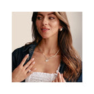 Femme portant un pendentif soleil en argent 925 avec pierres blanches, souriante et élégante.