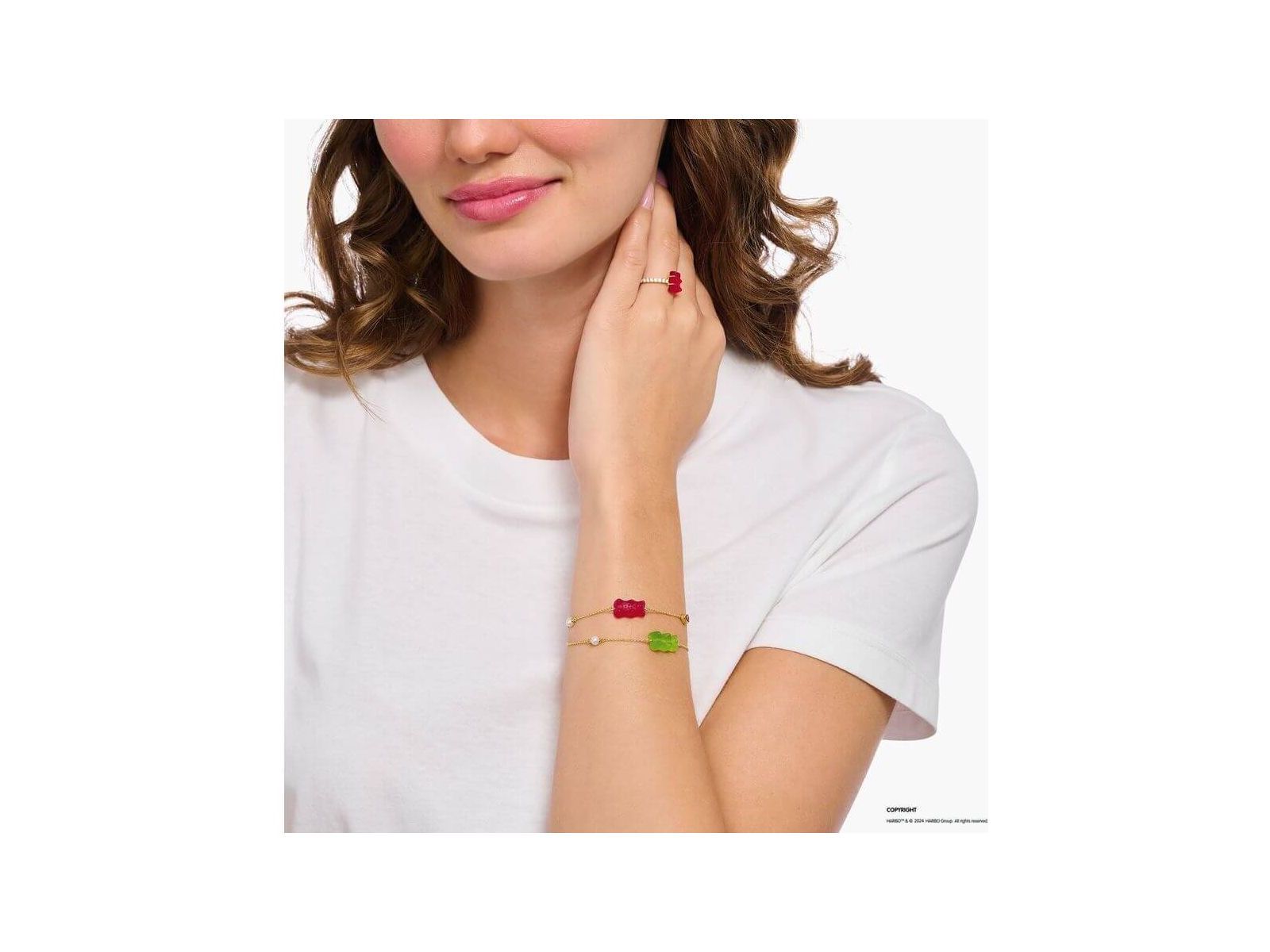 Femme portant un bracelet fantaisie avec ours d'or vert et perles, évoquant l'élégance et la nostalgie.