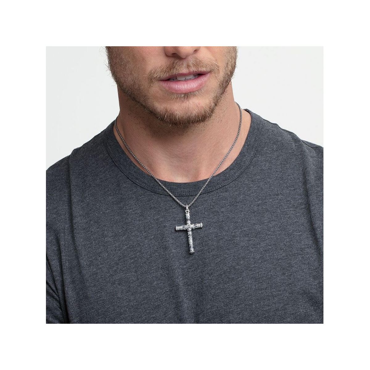 Homme portant un pendentif croix maori en argent, affichant élégance et tradition avec un design unique.