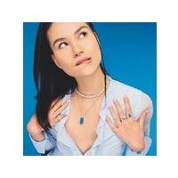 Model showcasing elegant jewelry against a blue background, featuring layered necklaces and rings.