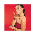 Femme faisant un geste de baiser, portant un bracelet avec Ours d’or rouge et autres bijoux raffinés.