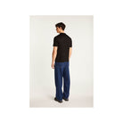 Homme de dos portant une chemise noire avec un pantalon bleu, montrant un style moderne et décontracté.