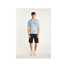 Homme portant un T-Shirt Marquez bleu ciel en coton biologique, associé à un short noir, style décontracté.