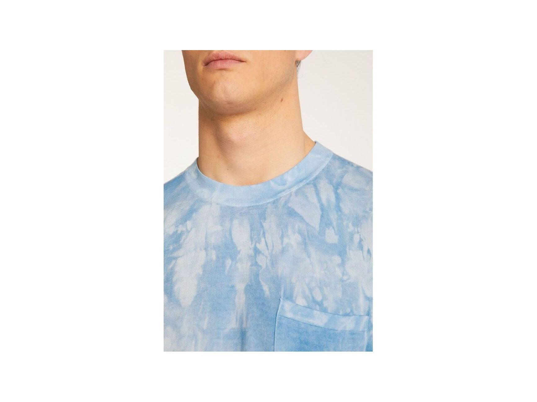 Close-up of a man wearing a light blue tie-dye t-shirt with a pocket, highlighting its modern design and comfort.