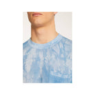 Close-up of a man wearing a light blue tie-dye t-shirt with a pocket, highlighting its modern design and comfort.