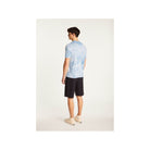Man wearing a light blue tie-dye T-shirt and black shorts, showcasing a modern casual style from the back.