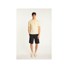 Homme portant un t-shirt jaune clair et un short noir, mettant en avant un look décontracté et élégant.