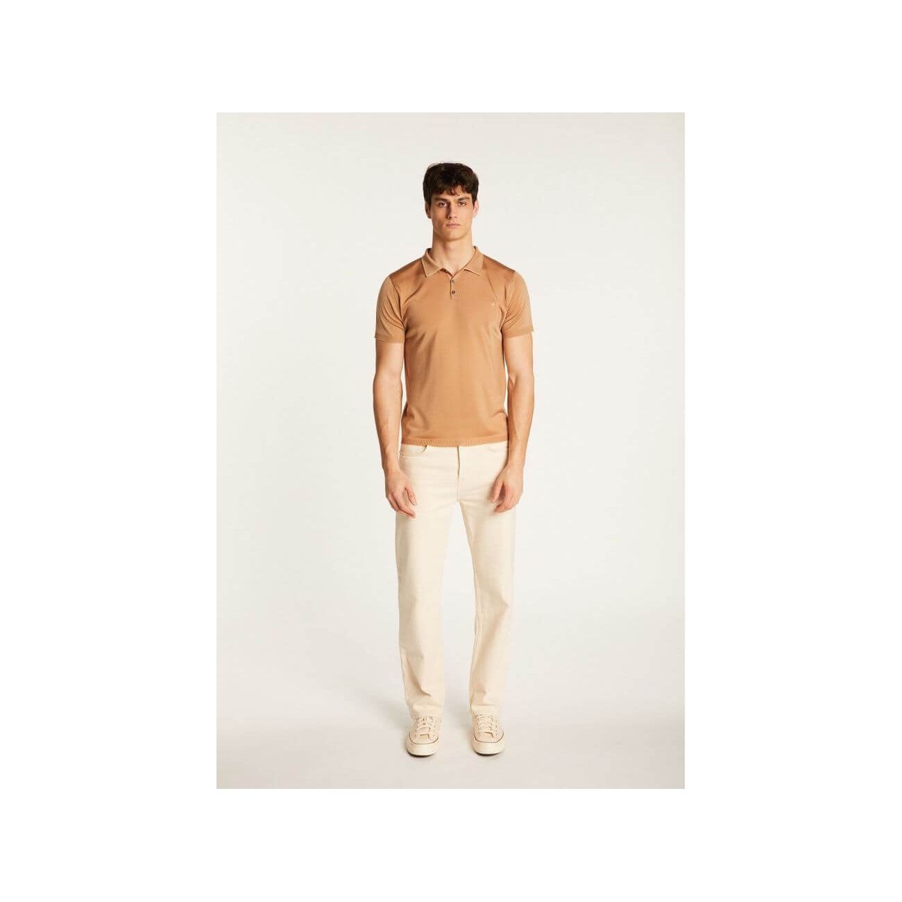 Homme portant un polo en Fil lumière Babar, couleur beige, avec pantalon clair et baskets.