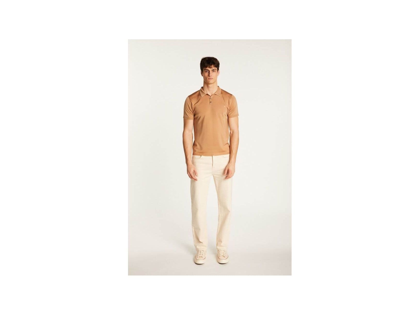 Homme portant un polo en Fil lumière Babar, couleur beige, avec pantalon clair et baskets.