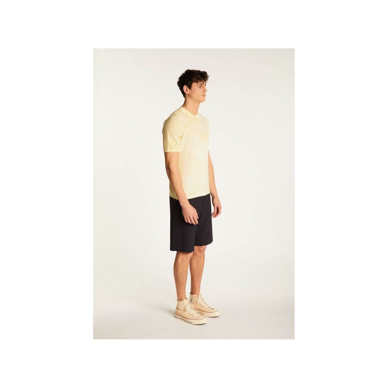 Model wearing a light yellow T-Shirt Marquez paired with dark shorts and sneakers.
