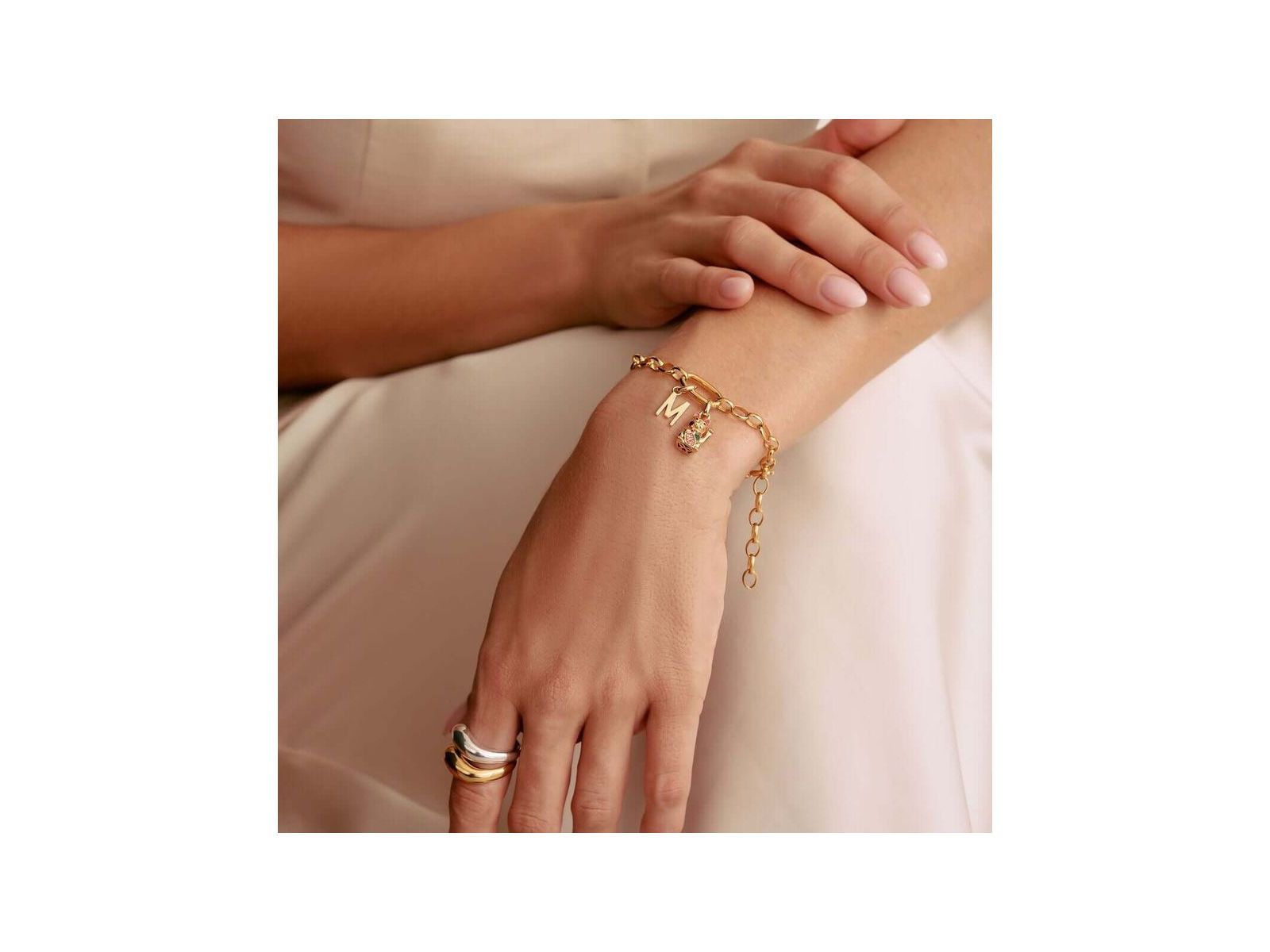 Bracelet charm en or avec lettres, design élégant et personnalisable, porté sur un poignet féminin.