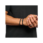 Homme portant un bracelet en obsidienne et zirconium noir, style rock-chic à la mode.