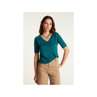 Femme portant un T-shirt teal à col V, en lin léger, associé à un pantalon beige.