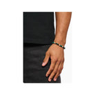 Homme portant un bracelet en beads verts et terre de 7 mm, accentué par une bague en argent.