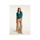 Modèle féminin en t-shirt turquoise et pantalon large beige, parfaite tenue décontractée pour l'été.