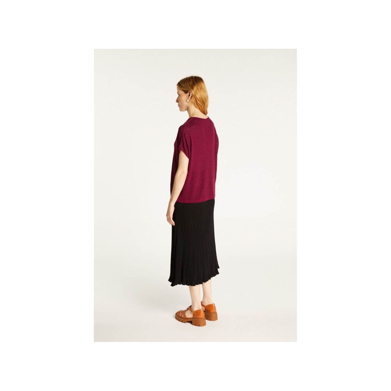 Model showcasing Larra T-shirt in flammé linen, paired with a black pleated skirt, highlighting comfort and style.