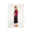 Model showcasing Larra T-shirt in flammé linen, paired with a black pleated skirt, highlighting comfort and style.
