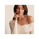 Femme élégante portant un pendentif charm trèfle 3D en argent, sourire et regard confiant.