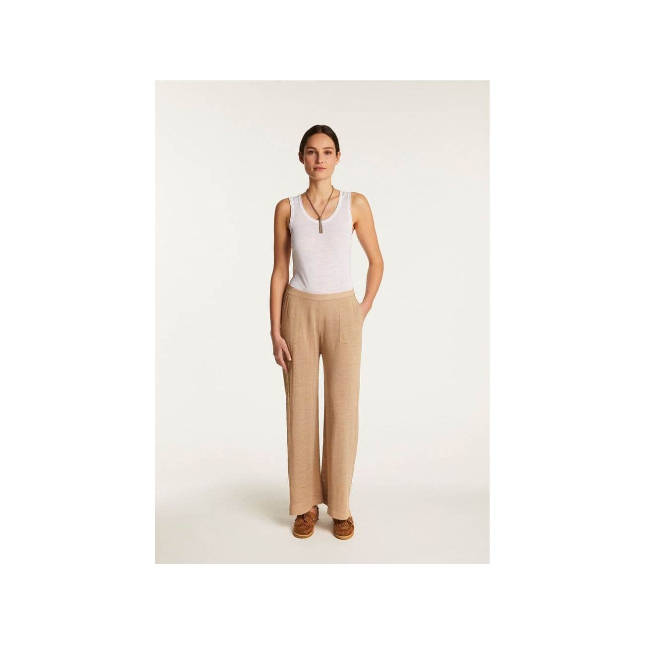 Debora linen flammé pants featuring a relaxed fit, paired with a white tank top for a casual yet elegant look.