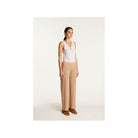 Model wearing beige PANTALON DEBORA en lin flammé with a white tank top, showcasing stylish elegance and comfort.