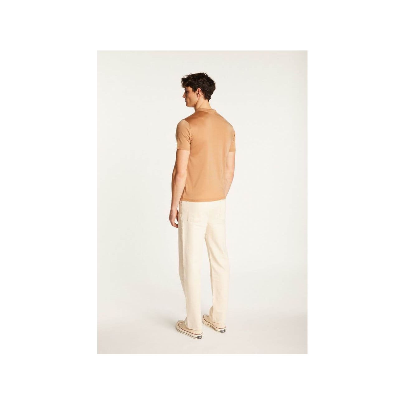 Back view of a man wearing a light brown short-sleeve polo and cream pants, showcasing a stylish and casual outfit.