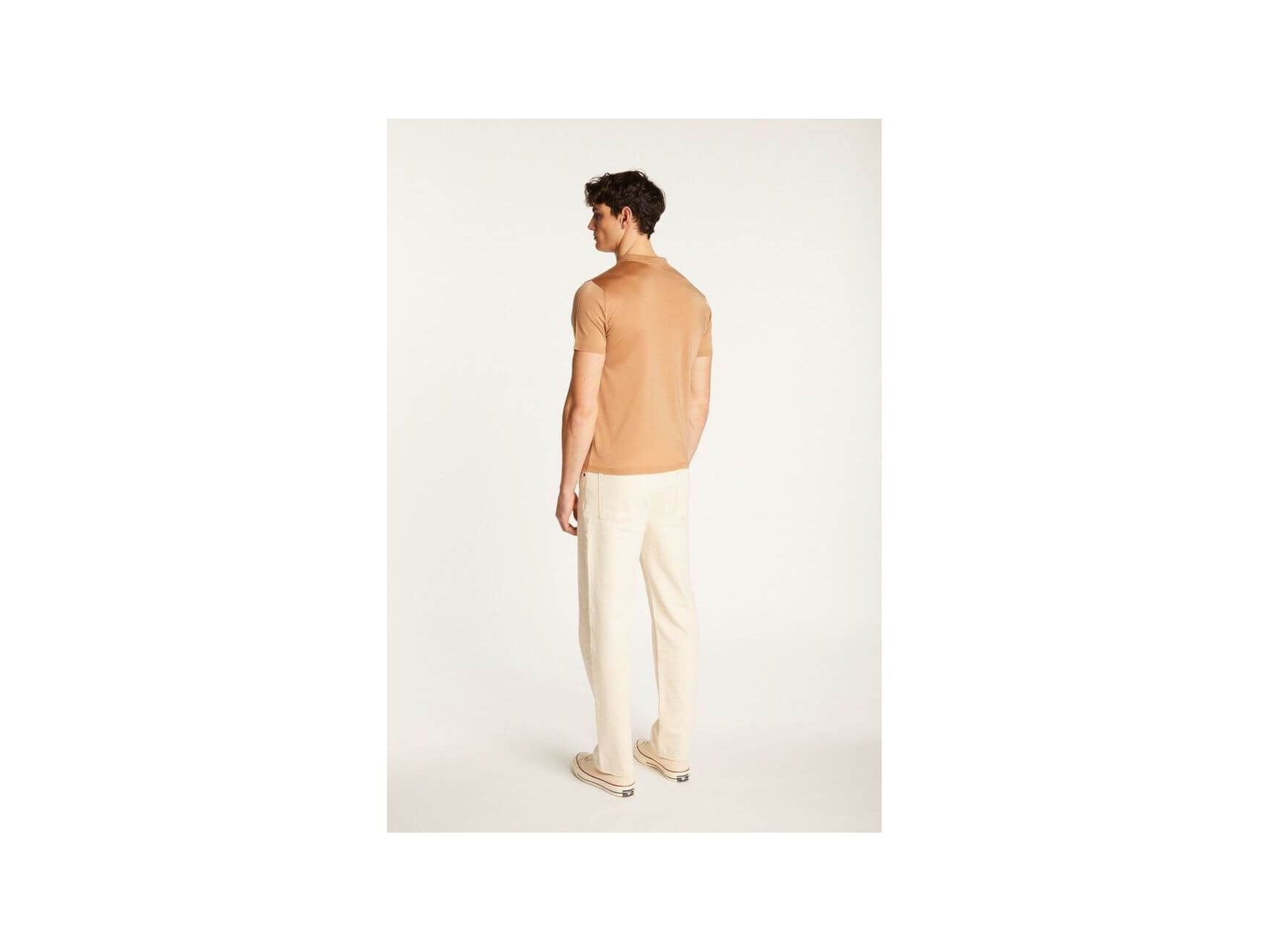 Back view of a man wearing a light brown short-sleeve polo and cream pants, showcasing a stylish and casual outfit.